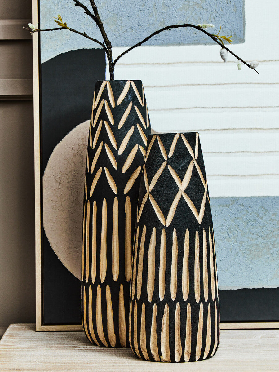 Two black wooden vases, with lighter carved details, on a sideboard