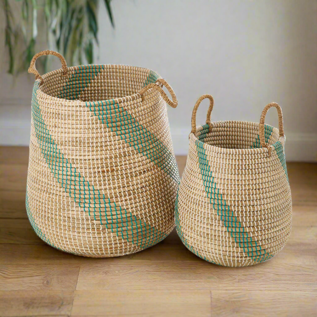 Two natural seagrass storage baskets, with green stripe details, sitting side by side on a plain white background