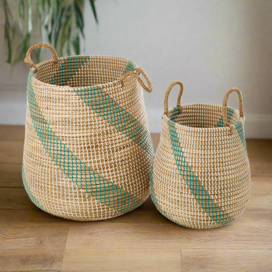 Two natural seagrass storage baskets, with green stripe details, sitting side by side on a plain white background