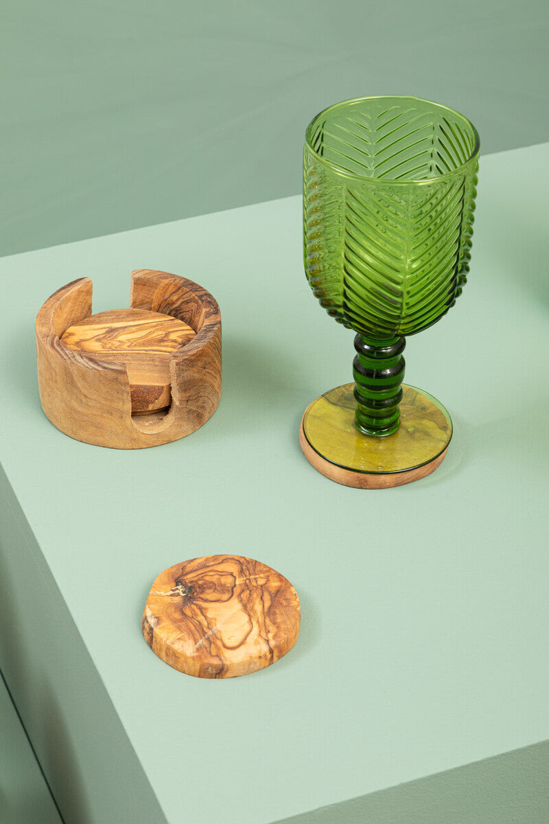 Set of four wooden coasters on a green countertop with a green glass